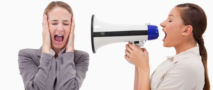 Young manager yelling at her employee through a megaphone against a white background