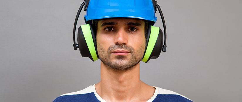 An image showing a man wearing PPE including ear defenders and a hard hat