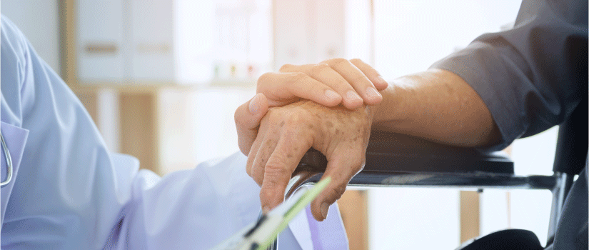一幅描绘老年人的手被医疗专业人员握住的图像。这张图片被用在一篇文章中，详细说明了老年痴呆症和听力损失之间的联系